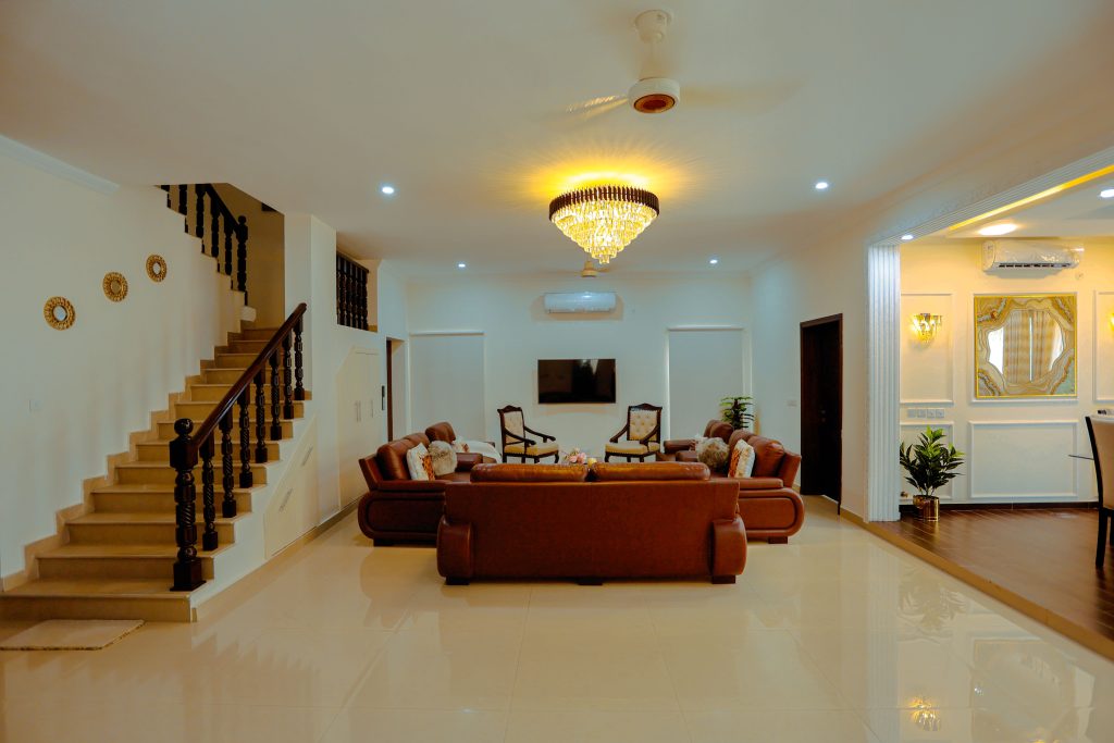 Spacious modern living room with leather sofas and elegant chandelier, ideal for real estate.