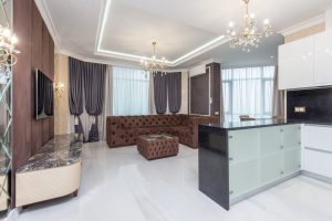 Spacious modern living room featuring elegant chandeliers, plush sofa, and contemporary decor.